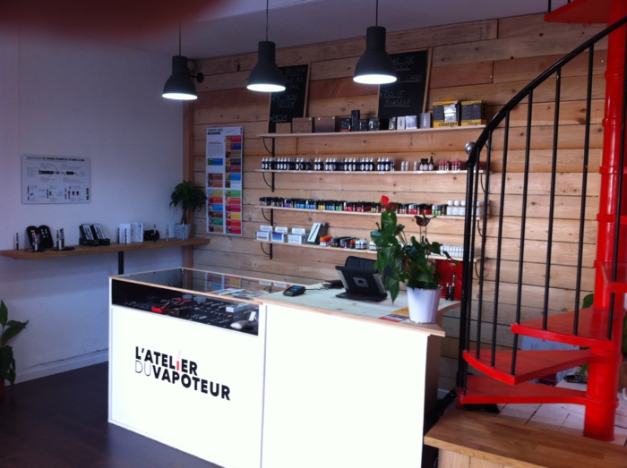 Intérieur de la boutique L'Atelier du Vapoteur, comptoir et présentoirs d'e-liquides