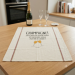 Torchon en coton écru humour champagne posé sur une table de cuisine