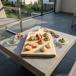Planche apéro bois avec des amuses bouche et posée sur une table dehors sur une terrasse