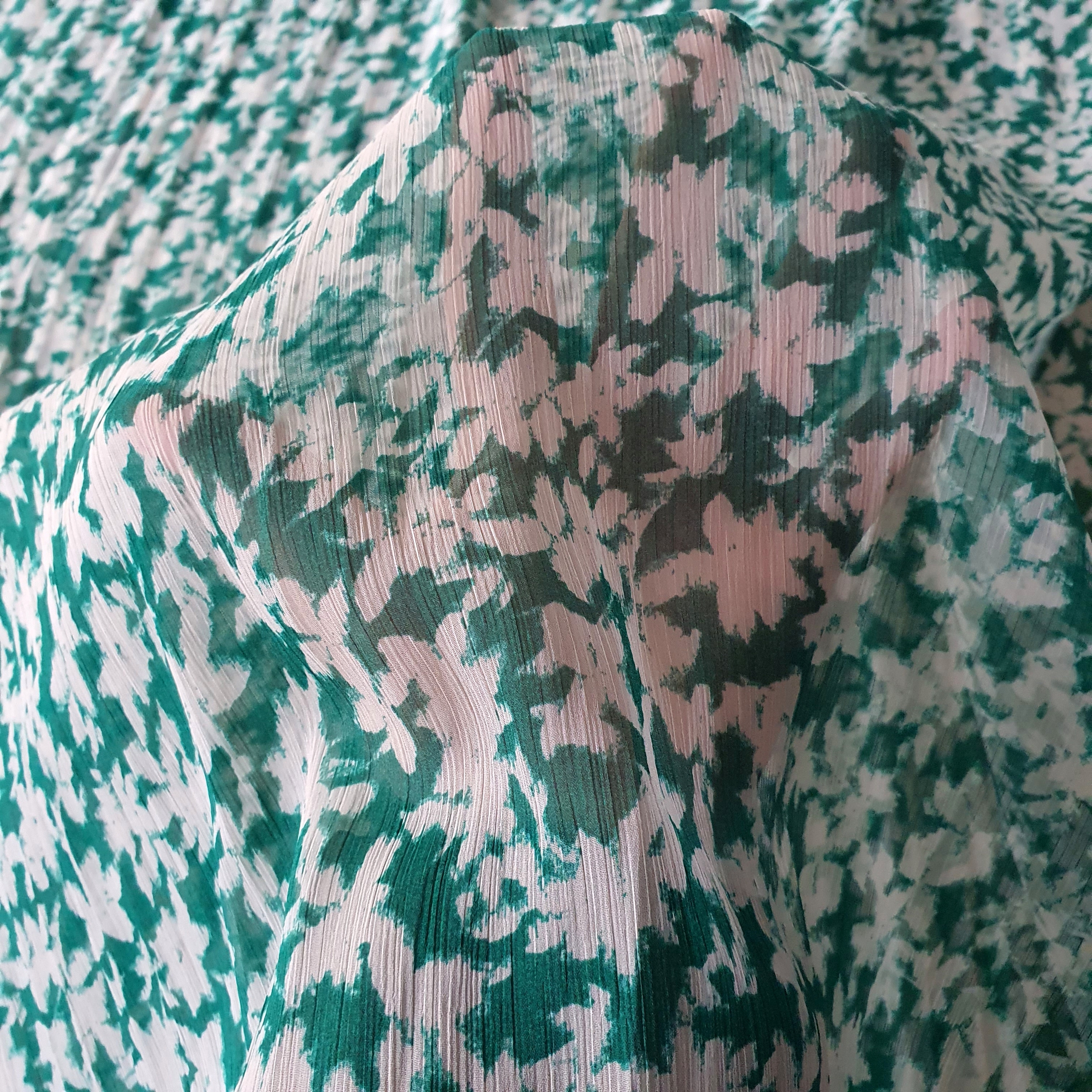 Tissu mousseline polyester fleuri blanc effet froissé sur fond vert. (1)