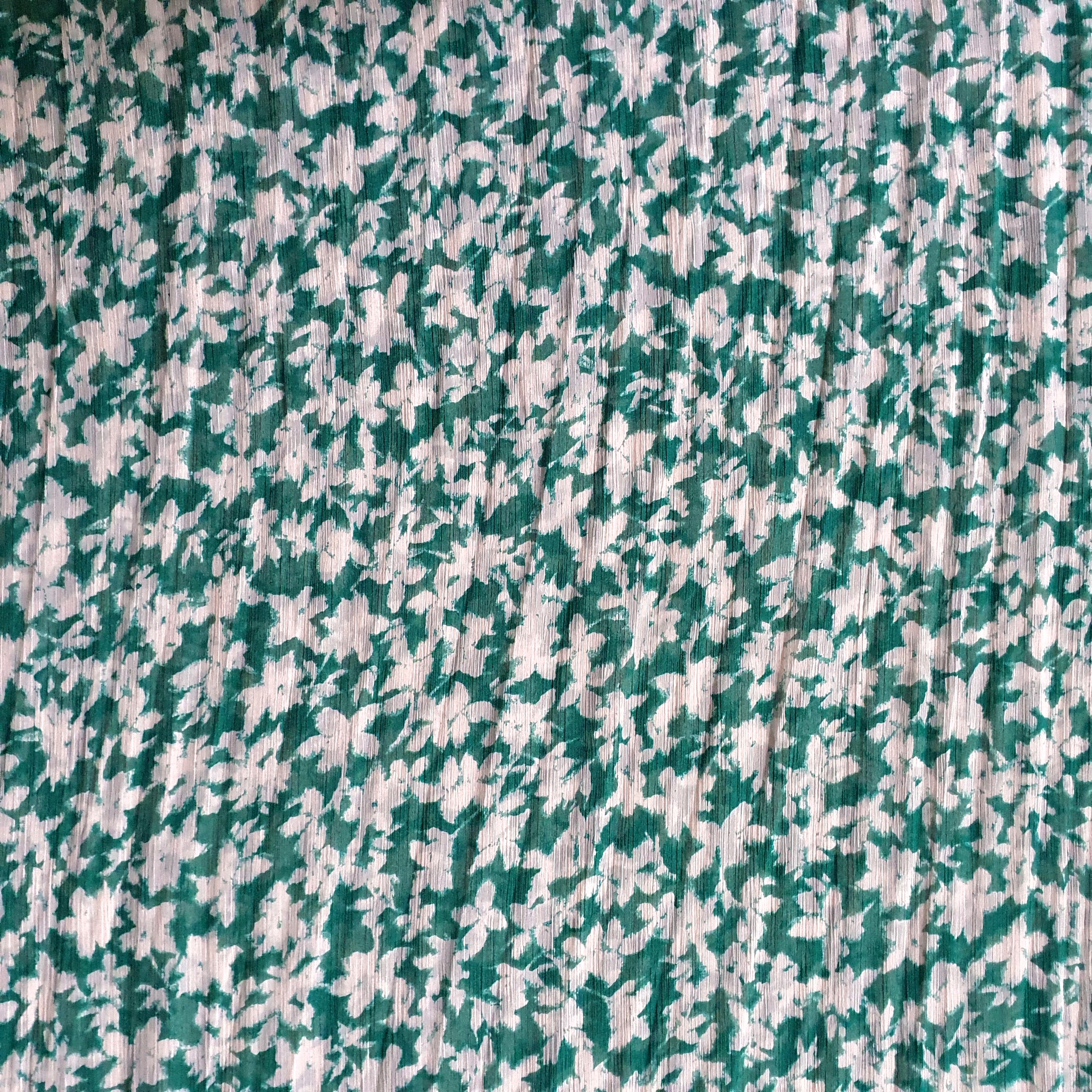 Tissu mousseline polyester fleuri blanc effet froissé sur fond vert