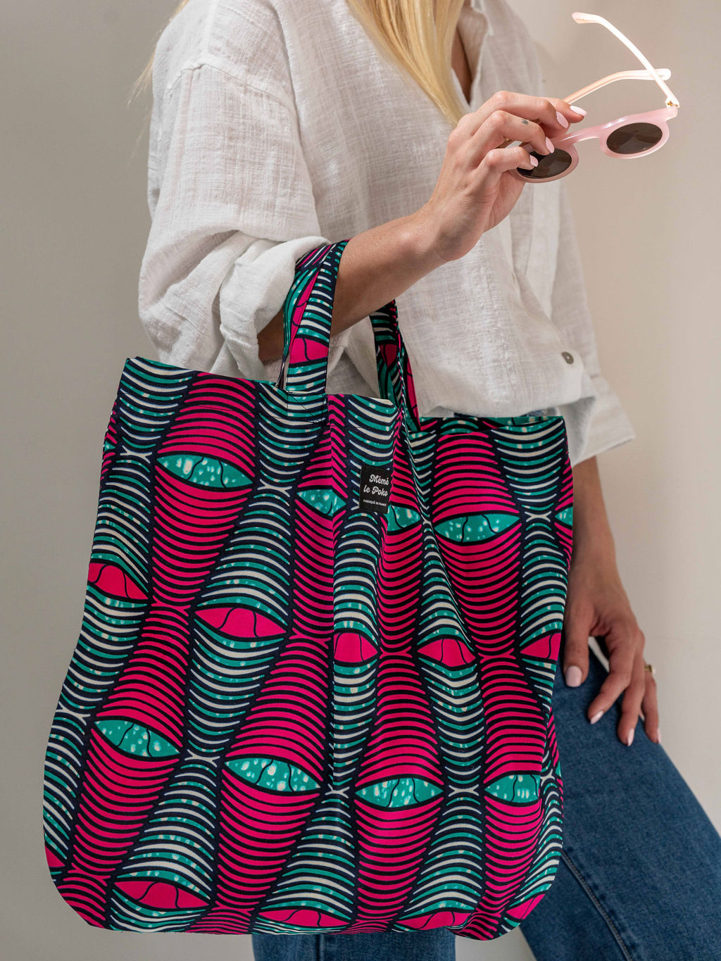 jeune femme tenant sac oeil de chat rose et vert