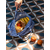 une main de femme tient un sac bleu posé au sol et rempli de fruits