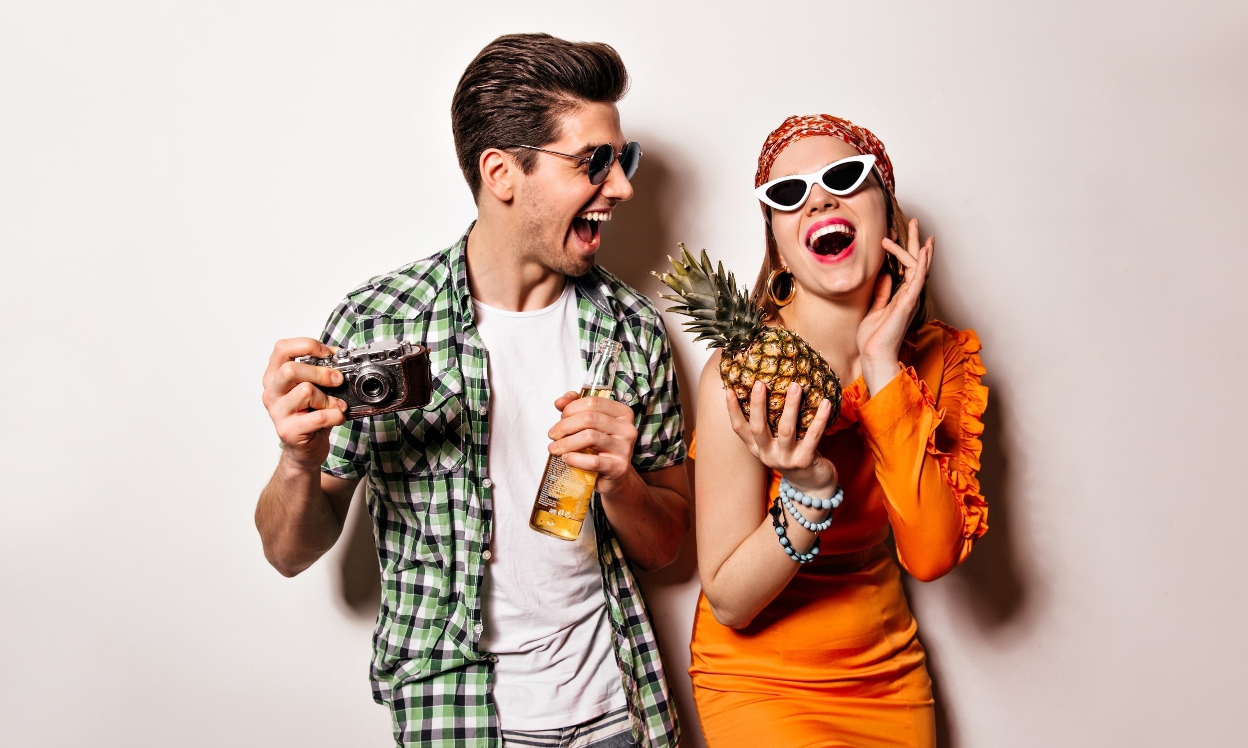 man woman stylish outfits sunglasses sincerely laugh pose with retro camera pineapple bottle beer white background
