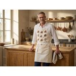 Jean portant le tablier de cuisine coton motif vache Aubrac dans sa cuisine - Retour dAubrac - aveyron