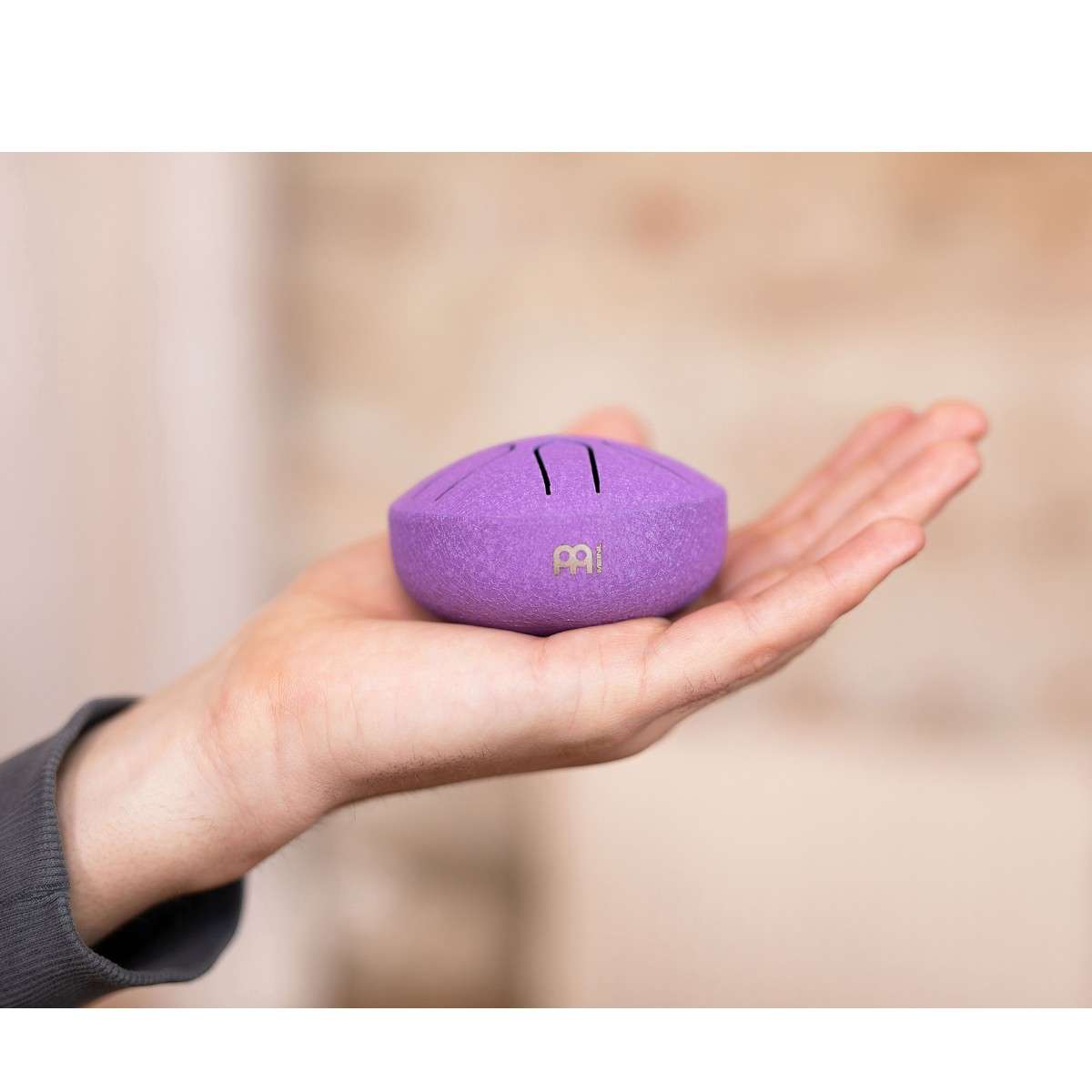 Vue latérale d’un mini tongue drum violet Meinl Sonic Energy tenu dans la main.