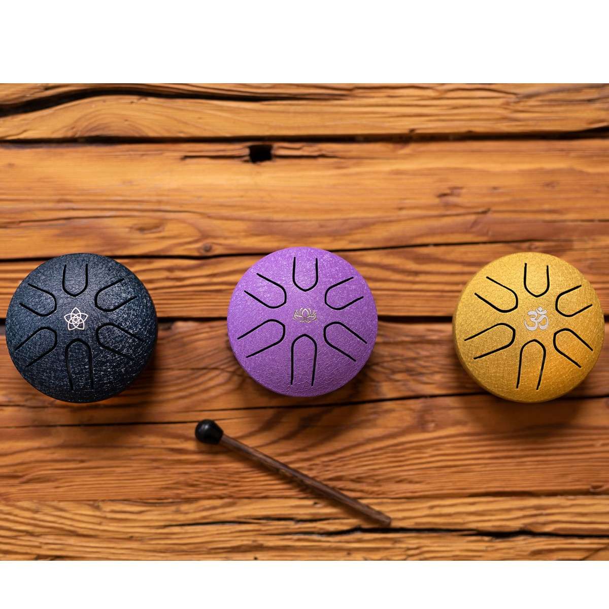 Trois mini tongue drums Meinl alignés sur une table en bois  coloris bleu nuit, violet et doré.