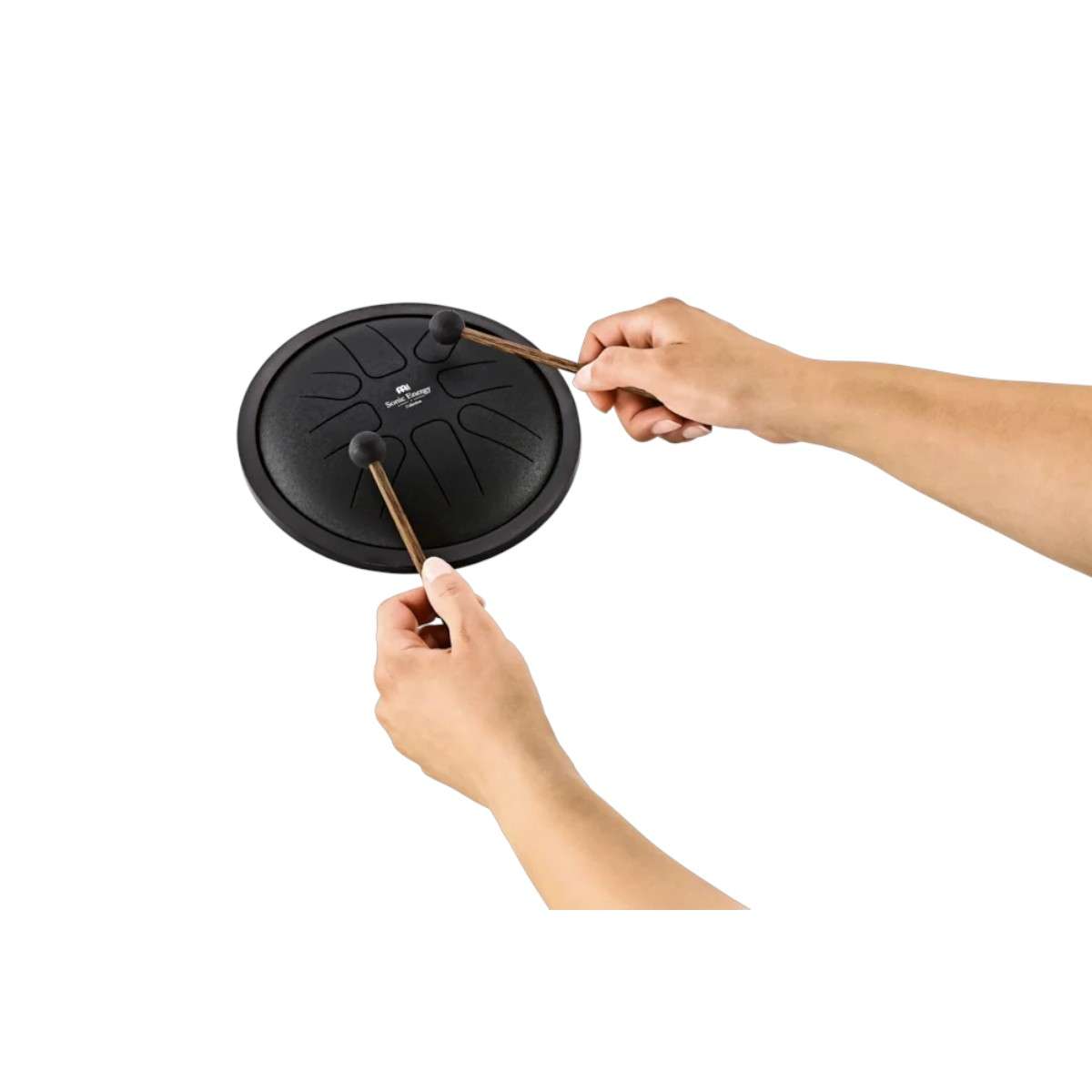 Tongue drum Meinl noir tenu à deux mains, gros plan sur la surface et les languettes