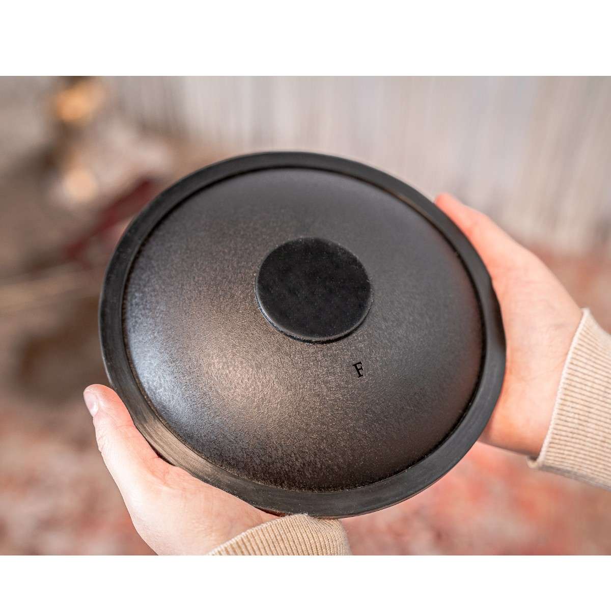 Vue arrière du mini tongue drum Meinl noir tenu dans les mains, finition texturée