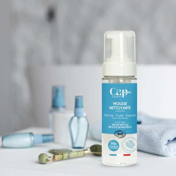 Flacon de mousse nettoyante visage bio Cap Hydra posé dans une salle de bain avec accessoires de beauté.