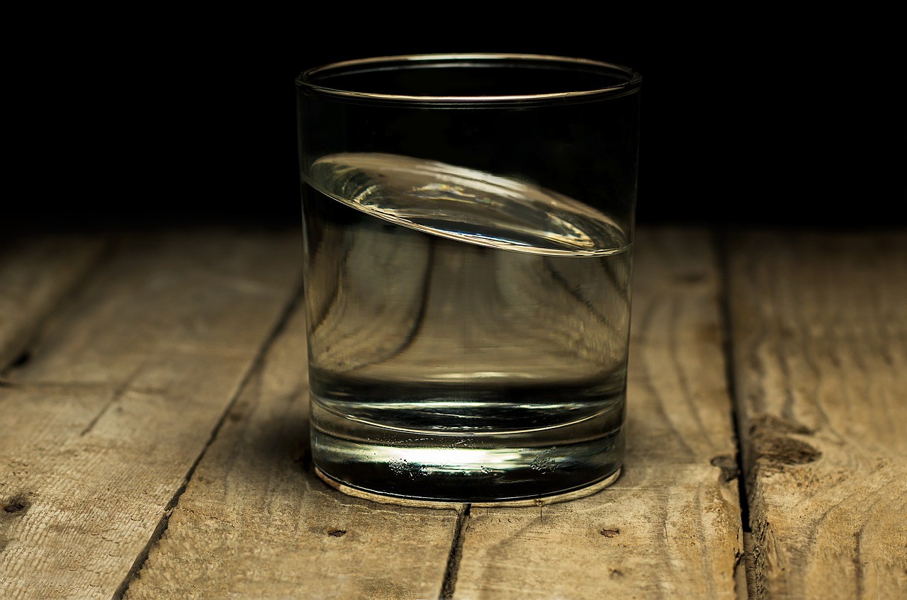 Verre d'eau claire posé sur une table en bois, illustrant l'hydratation quotidienne avec eau alcaline