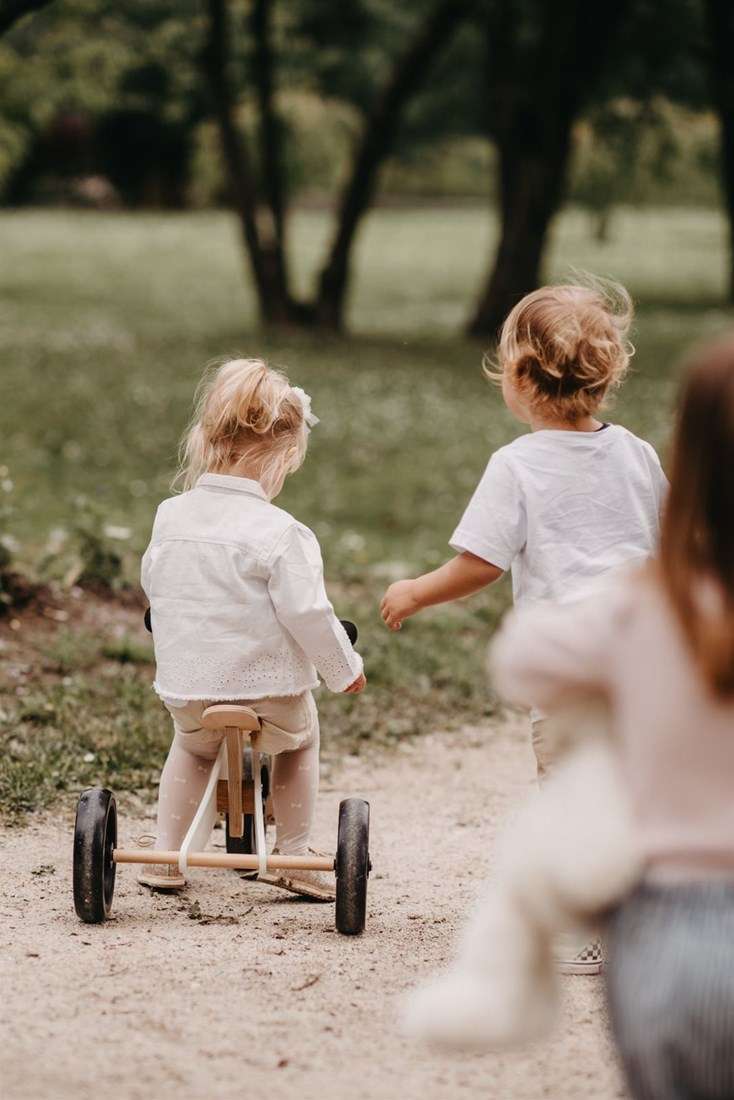 Enfant roulant sur le tricycle Tiny Tot Plus blanc Kinderfeets dans un chemin de parc