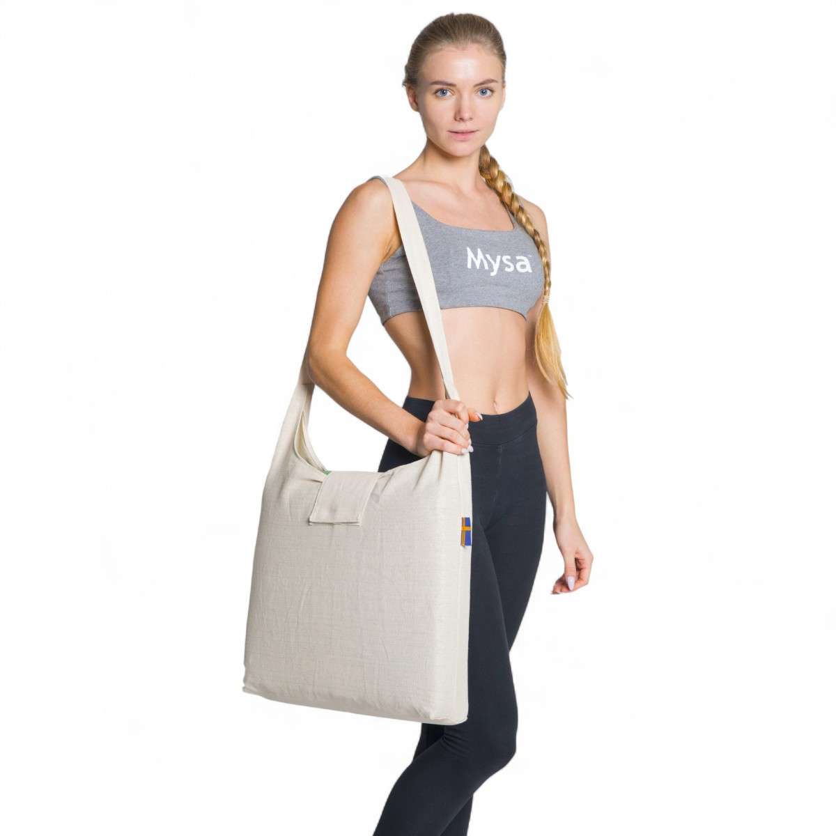 Femme portant sur l’épaule le sac beige de transport du tapis Mysa XXL