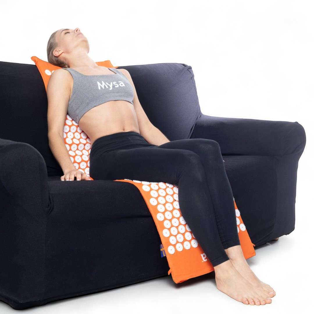 Femme allongée sur le tapis Magnetic Mysa XXL installé sur un canapé pour une séance de détente.