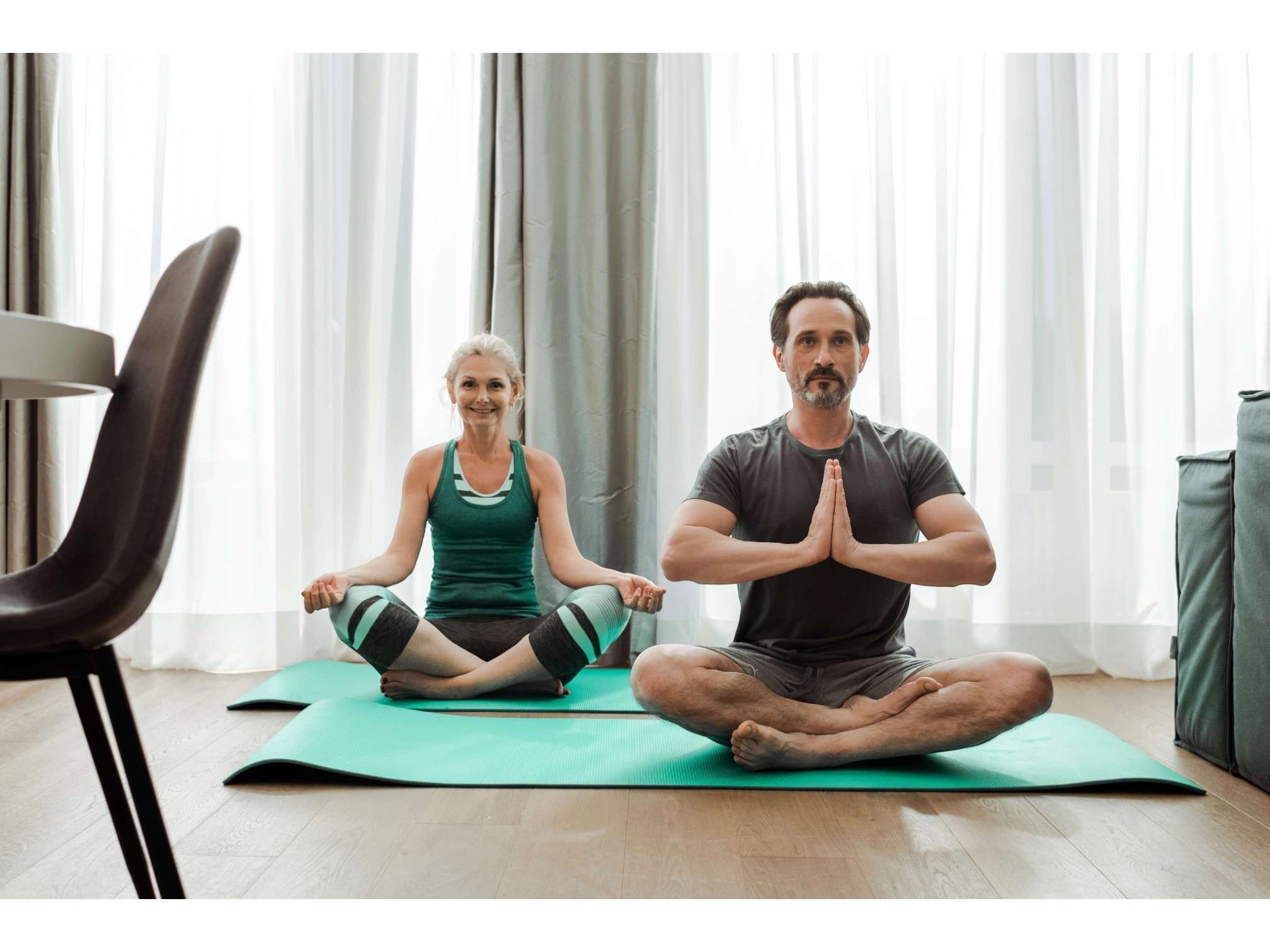 Couple de quinquagénaires assis sur un tapis de yoga en position de méditation, activité douce pour les articulations