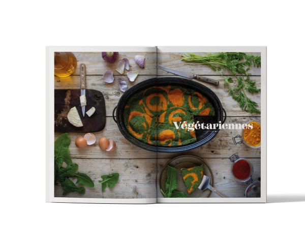 Livre de recettes cocotte roaster ouvert sur une double page consacrée aux recettes végétariennes, avec légumes, herbes fraîches et cocotte Graniteware