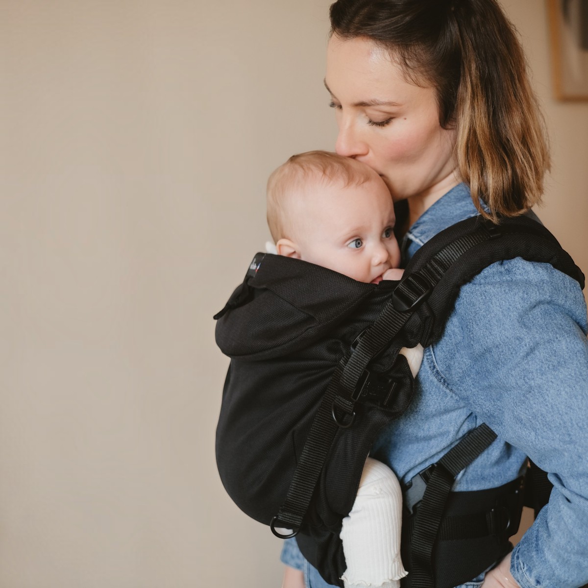 Néo+ Néobulle coloris NoirÉbène, porté devant, maman qui embrasse son bébé