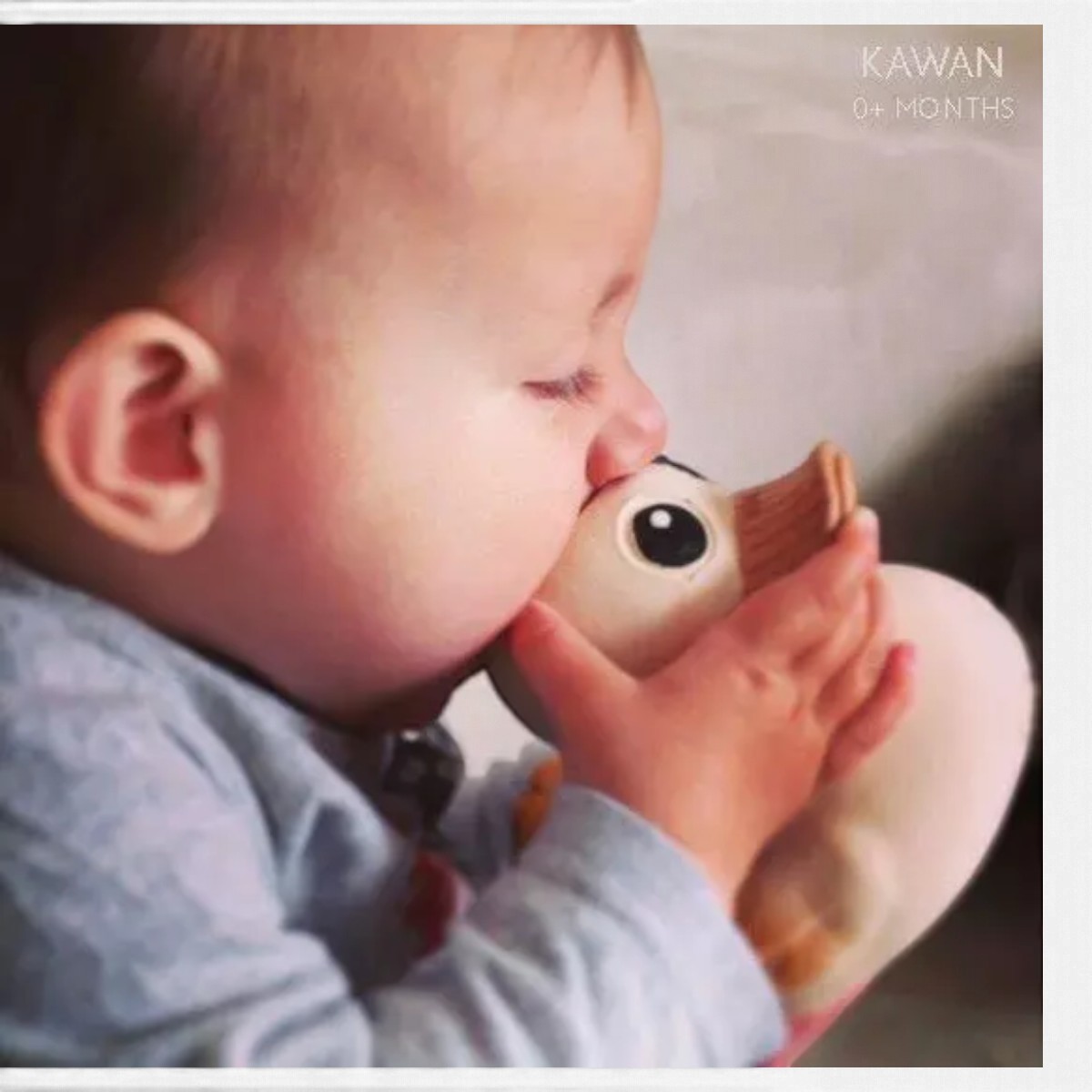 Bébé tenant le canard Kawan Original HEVEA à deux mains et mordillant son bec texturé