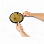 Gros plan sur les mains jouant du mini tongue drum doré avec deux maillets