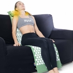 Femme assise sur un canapé avec le tapis Mysa le long du dos et le coussin chauffant sous les cervicales