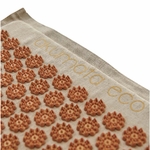 Détail des pointes d’acupression dorées Akumata Eco sur tissu en lin naturel