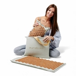 Femme présentant le tapis d’acupression Akumata Eco avec pointes dorées et le sac de transport