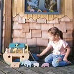 Enfant jouant dehors avec l’Arche de Noé Tender Leaf, faisant monter les animaux sur l’échelle.