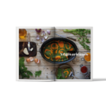 Livre de recettes cocotte roaster ouvert sur une double page consacrée aux recettes végétariennes, avec légumes, herbes fraîches et cocotte Graniteware