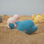 Dauphin bleu Tikiri en caoutchouc naturel sur le sable, poulpes roses et crabe jaune derrière lui
