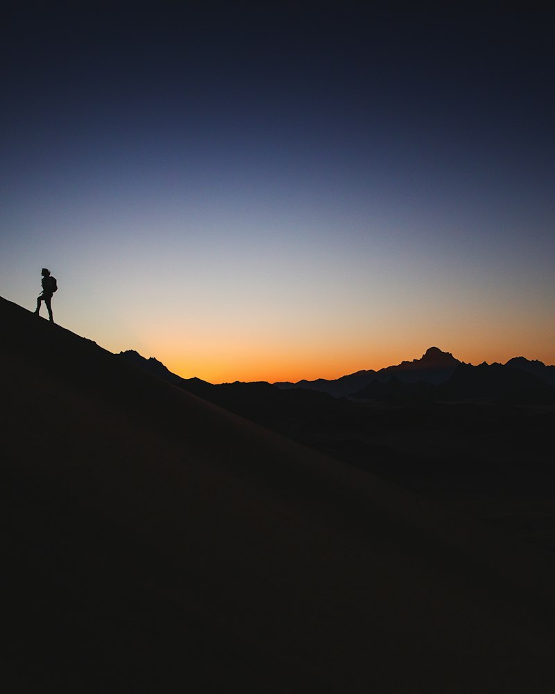 Silhouette d'un coureur sur une pente à la tombée de la nuit