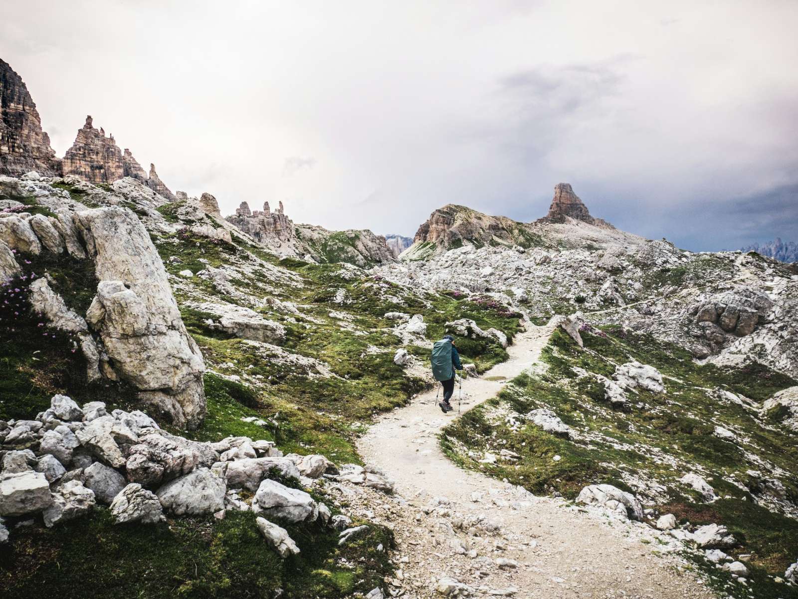 Coureur sur un sentier caillouteux entre les aiguilles calcaires des Dolomites