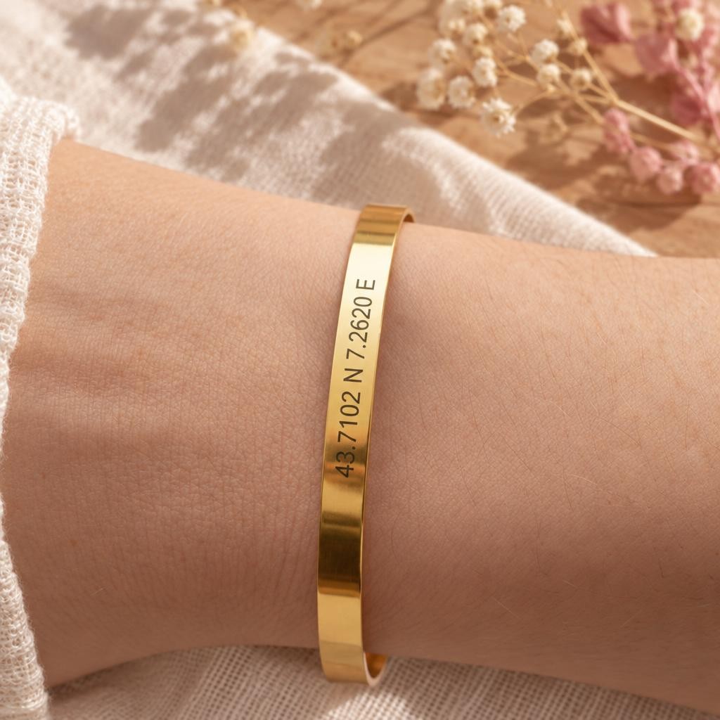 Bracelet jonc doré gravé de coordonnées GPS porté au poignet