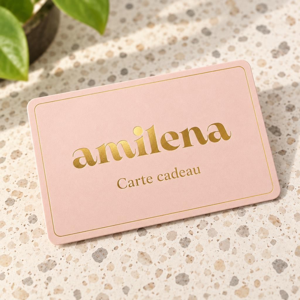 Carte cadeau Amilena rose avec logo doré posée sur un plan en terrazzo