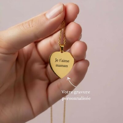 Collier coeur doré gravé Je t'aime maman tenu entre les doigts