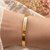 Bracelet jonc doré gravé de coordonnées GPS porté au poignet