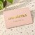 Carte cadeau Amilena rose avec logo doré posée sur un plan en terrazzo