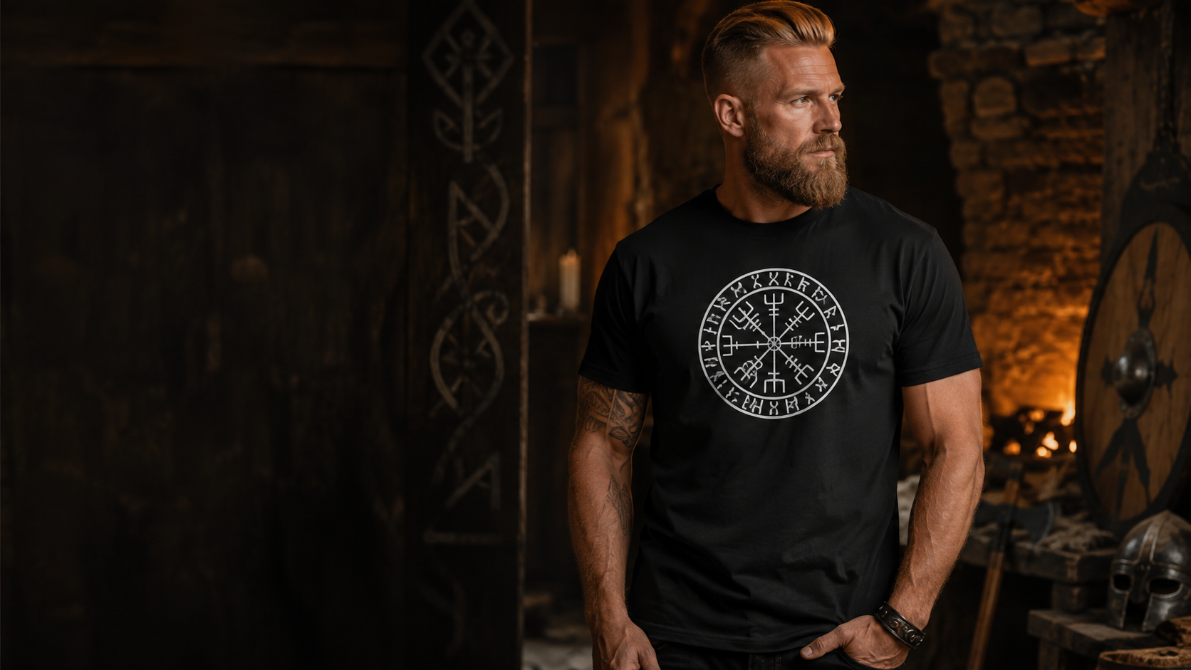Homme portant un T-shirt Viking noir Vegvisir dans une ambiance nordique avec bouclier, heaume et lumière de forge