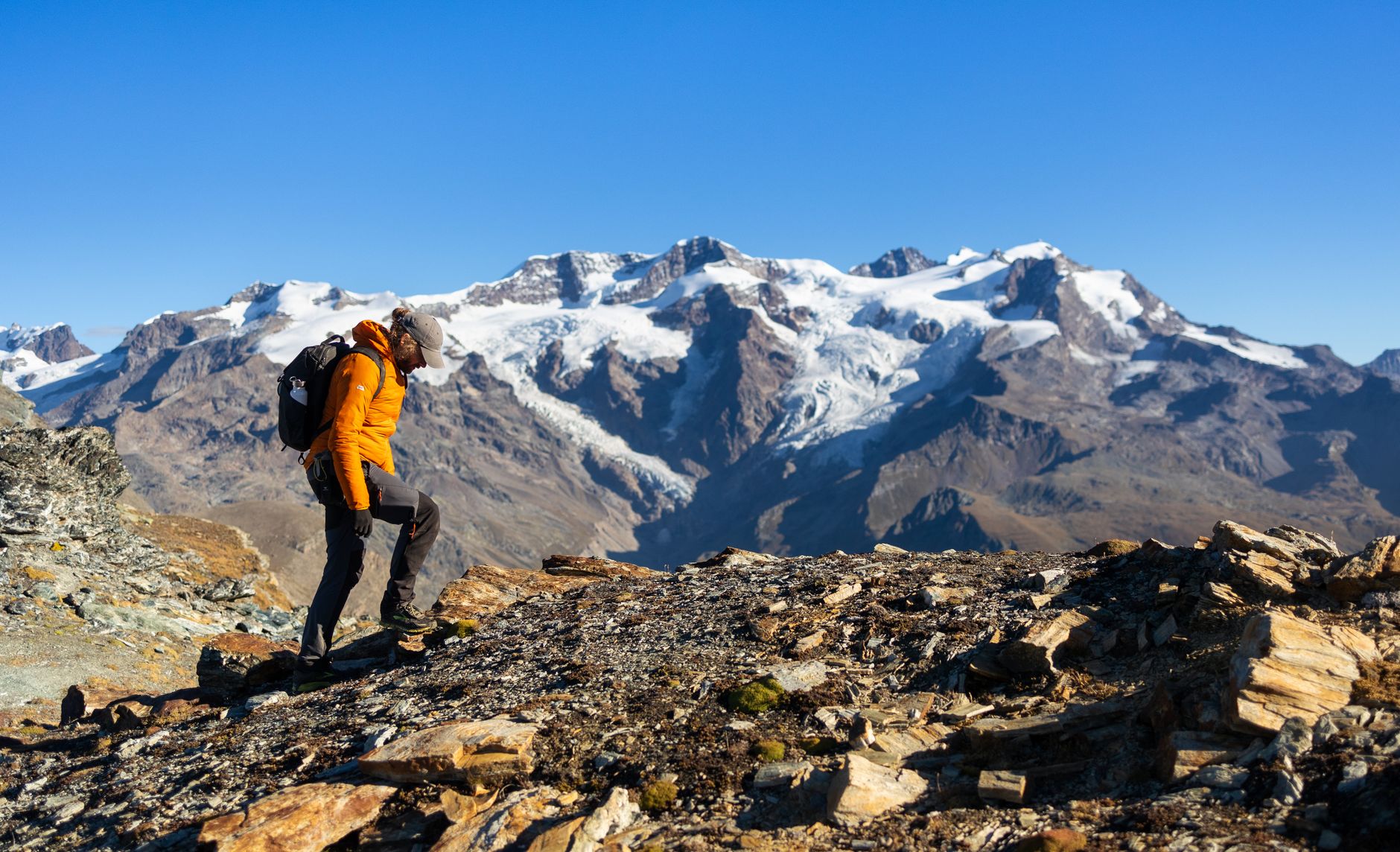 Randonneur en montagne analysant son itinéraire et le dénivelé positif face aux sommets enneigés