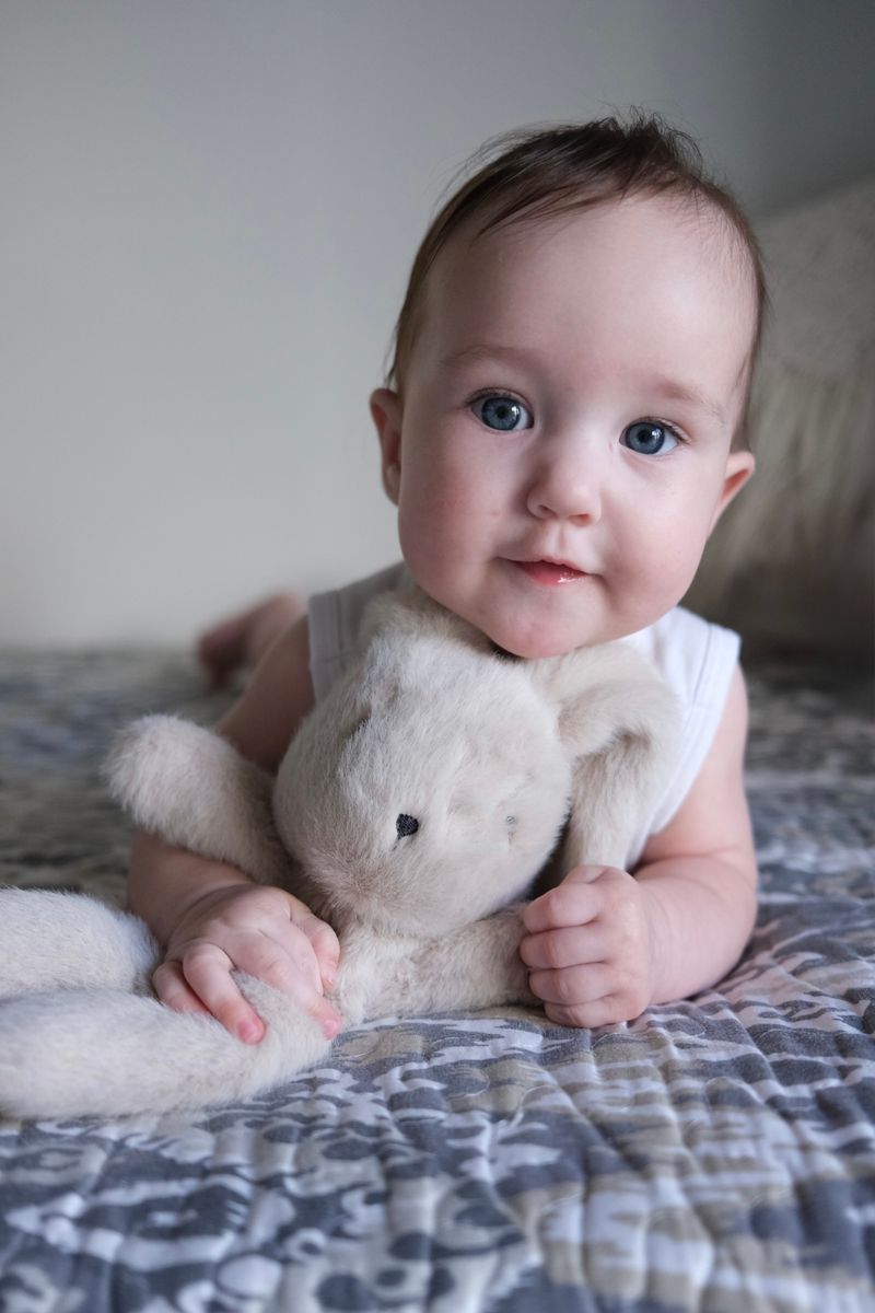un bebe mignon calinant une peluche sur un lit douillet a l interieur