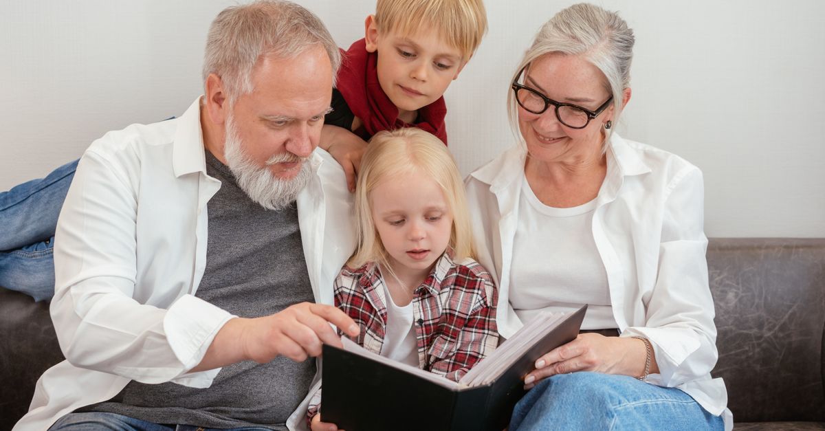 des grands parents et des petits enfants feuilletant un album photo sur le canape celebrant les liens familiaux et l amour