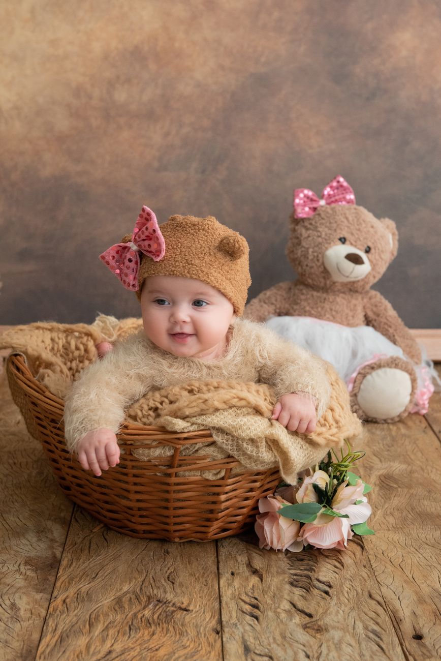 Jolie bébé fille dans un panier avec un ours en peluche dans un cadre de studio