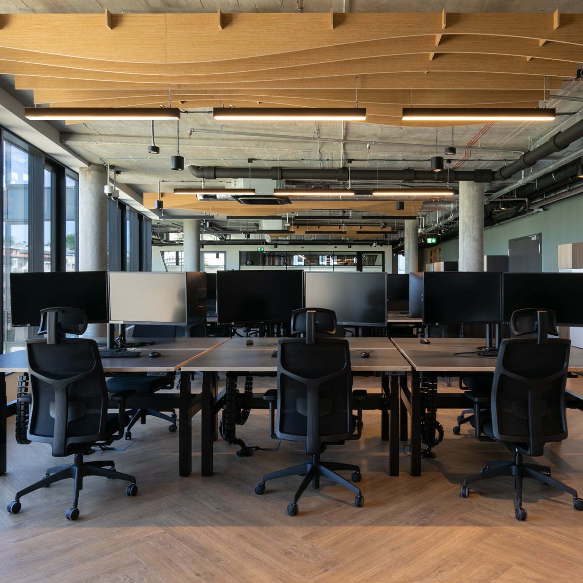 Bureaux doubles assis-debout Ogi Drive à plateaux sombres et structure noire dans un grand open space