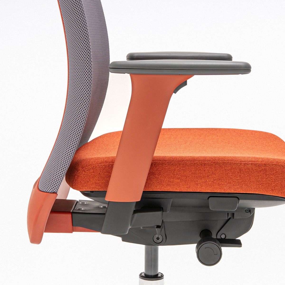 Chaise de bureau à cadre brique, résille grise et assise orange : accoudoir et mécanisme vus de profil