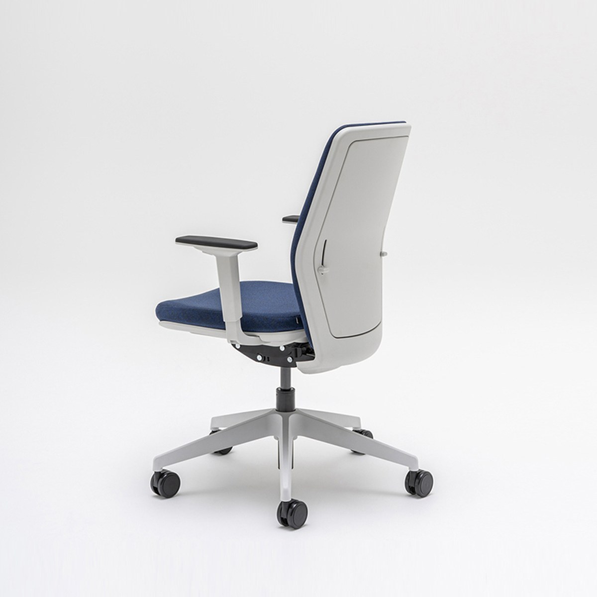 Chaise de bureau tapissée bleue vue de trois quarts arrière, coque de dossier grise