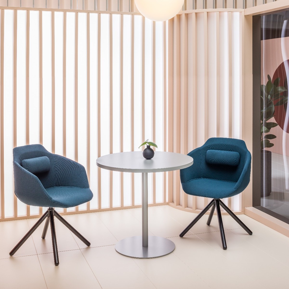 Petite table ronde Tack grise sur pied central aluminium entre deux fauteuils bleus