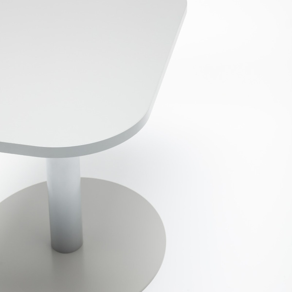 Détail de langle arrondi du plateau et de lembase disque en acier de la table Tack