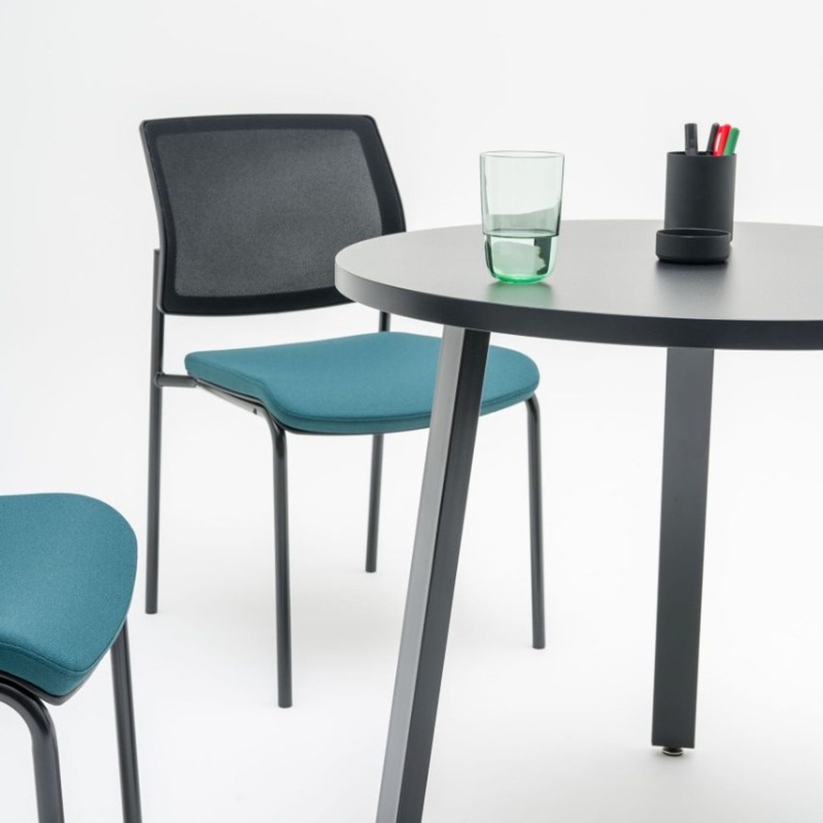 Détail dun pied incliné en acier anthracite et du plateau rond de la table Ogi A