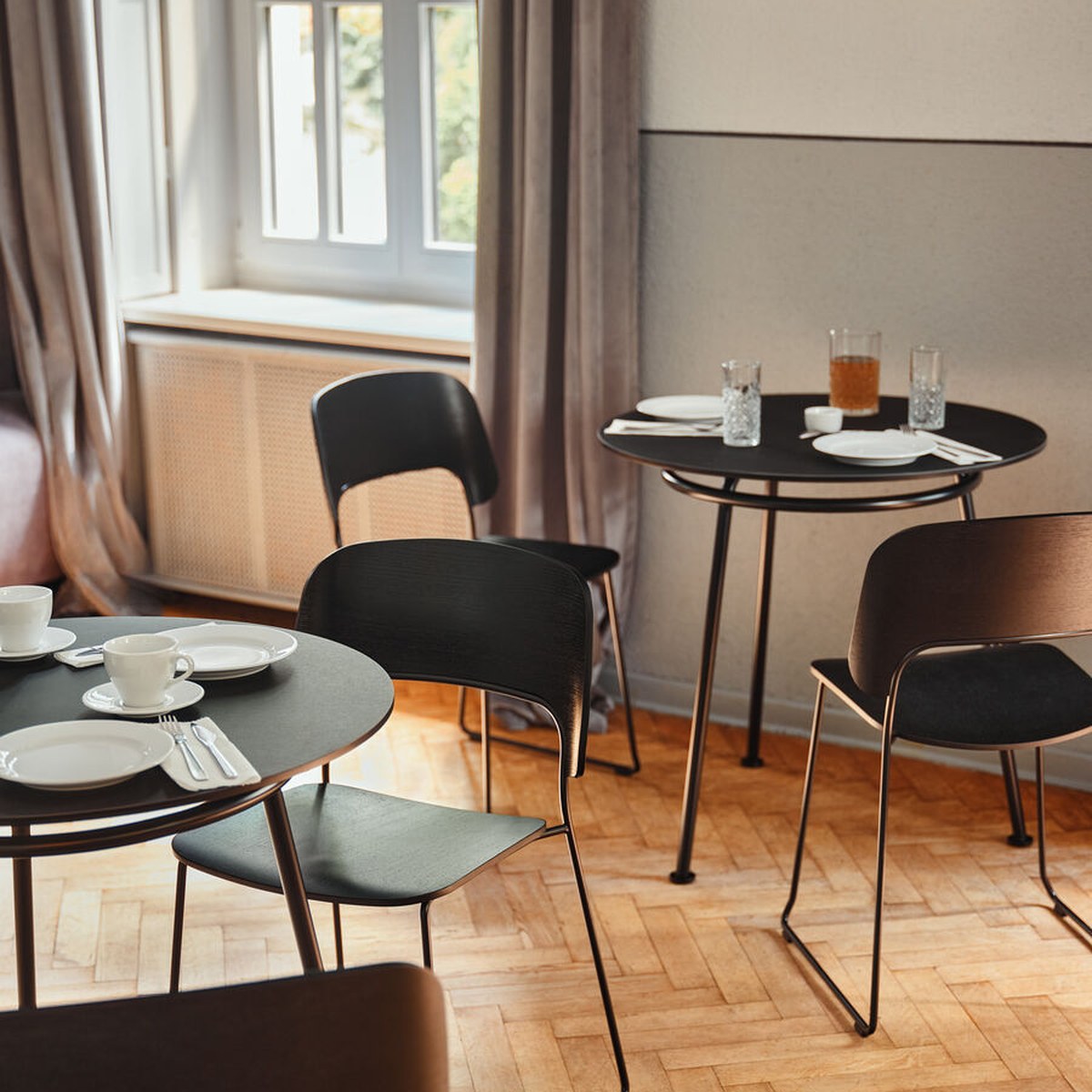 Tables rondes New School noires dressées pour un repas, avec des chaises en bois noir