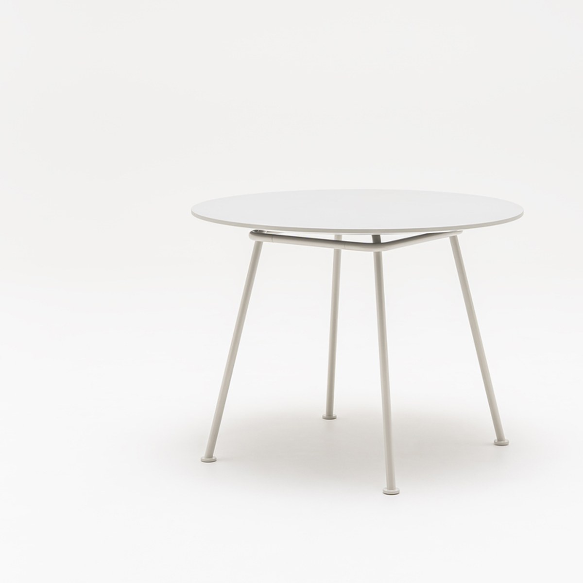 Table ronde New School gris clair à quatre pieds en tube métal, vue de trois quarts sur fond blanc