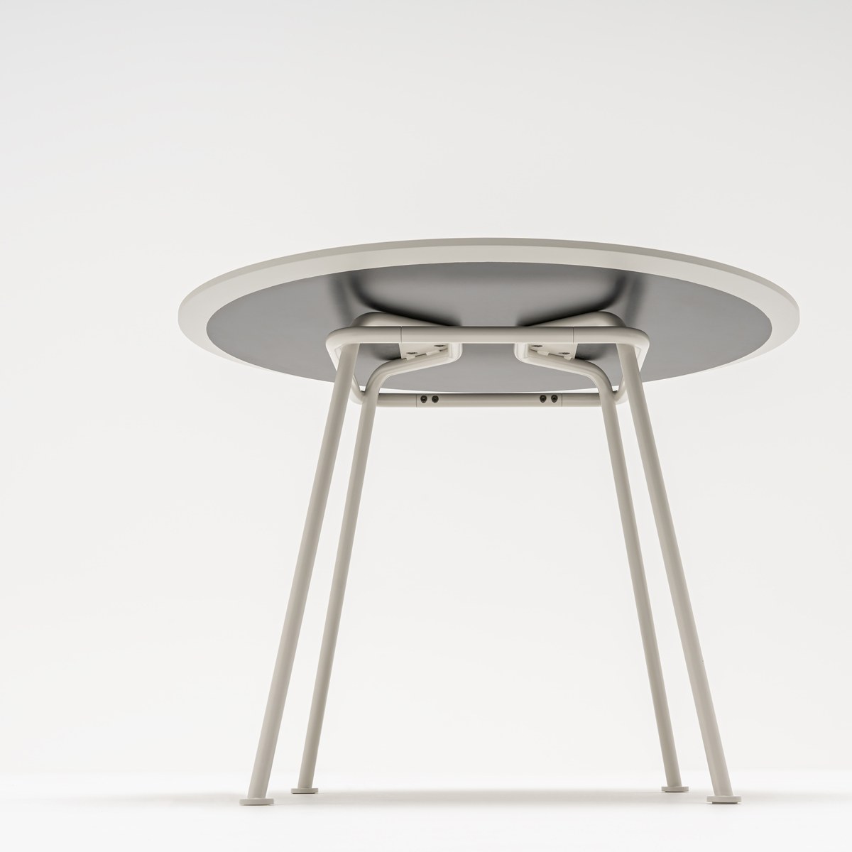 Dessous de la table ronde New School gris clair : tubes courbés de la structure fixés sous le plateau
